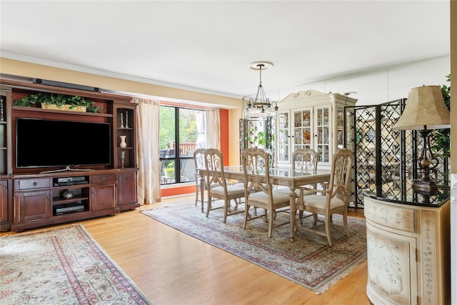 dining space with a chandelier, ornamental molding, and light wood finished floors