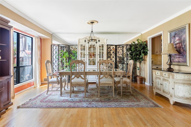 dining area featuring crown molding, baseboards, a chandelier, and wood finished floors
