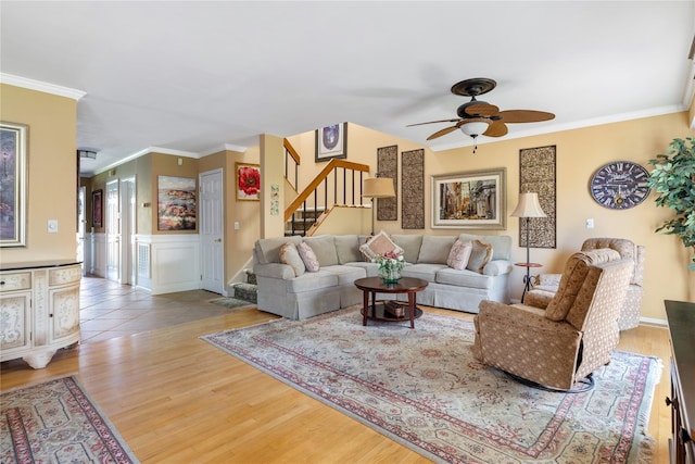 living room featuring a ceiling fan, wood finished floors, stairway, and ornamental molding