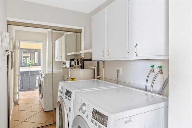 laundry area with water heater, washing machine and dryer, cabinet space, and light tile patterned flooring