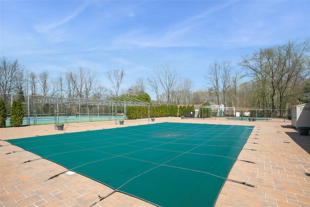 view of swimming pool with fence and a tennis court