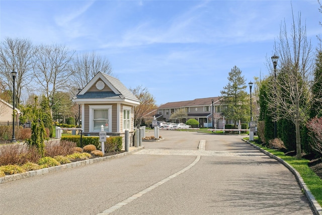 view of road with a residential view, a gated entry, street lighting, and curbs