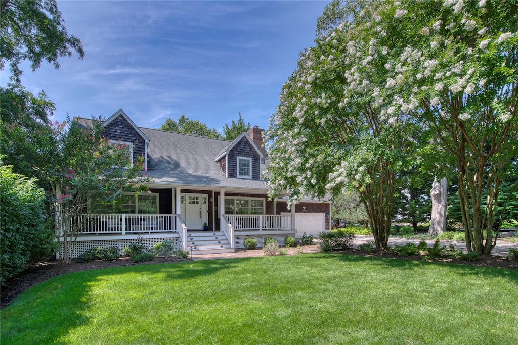 1065 W Mill Rd, Mattituck, NY 11952 - cape cod-style house with covered porch, a chimney, a garage, a front lawn, and a shingled roof
