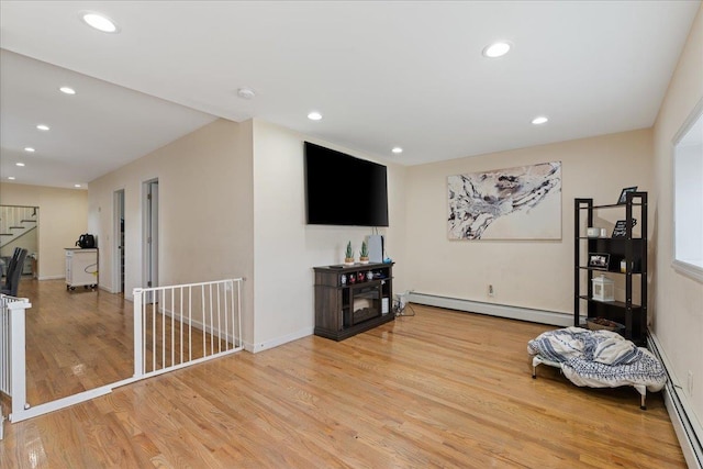living area featuring a baseboard heating unit, recessed lighting, wood finished floors, and baseboards