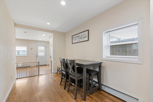 dining space featuring wood finished floors, recessed lighting, a baseboard heating unit, and baseboards