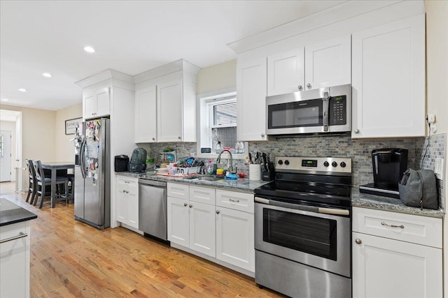kitchen featuring recessed lighting, tasteful backsplash, appliances with stainless steel finishes, a sink, and white cabinetry