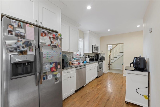 kitchen with recessed lighting, light wood-style flooring, decorative backsplash, appliances with stainless steel finishes, and white cabinetry