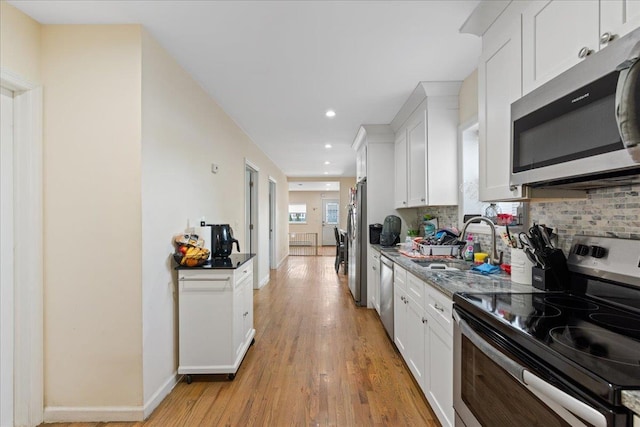 kitchen with white cabinets, a sink, appliances with stainless steel finishes, light wood-style floors, and recessed lighting