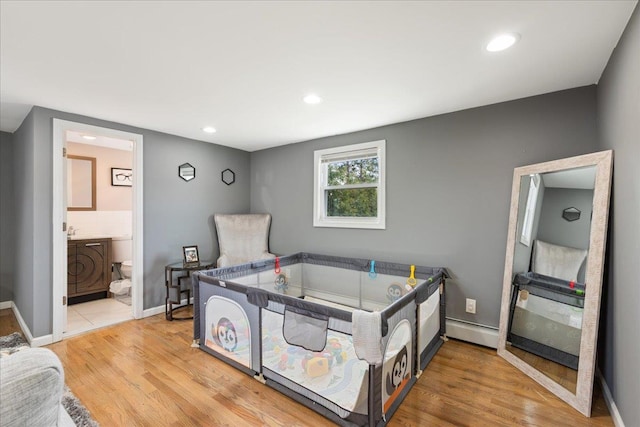 bedroom with a baseboard heating unit, recessed lighting, connected bathroom, and light wood-style floors