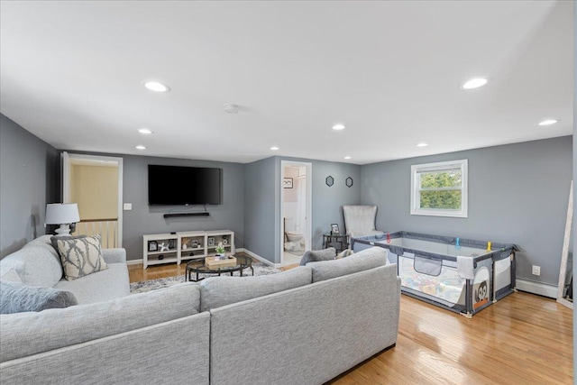 living room featuring baseboard heating, recessed lighting, light wood-style floors, and baseboards