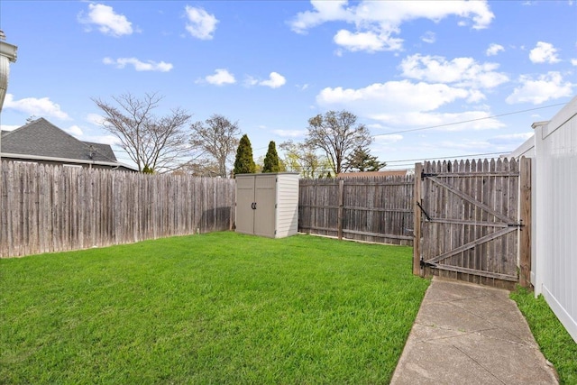 view of yard featuring a storage unit, a gate, an outbuilding, and a fenced backyard