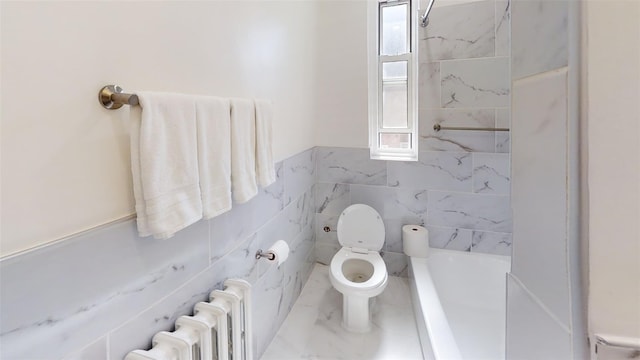 full bath featuring marble finish floor, toilet, tile walls, radiator heating unit, and a bath