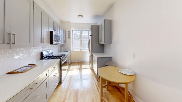 kitchen featuring light wood-type flooring, light countertops, gray cabinets, a sink, and stainless steel appliances