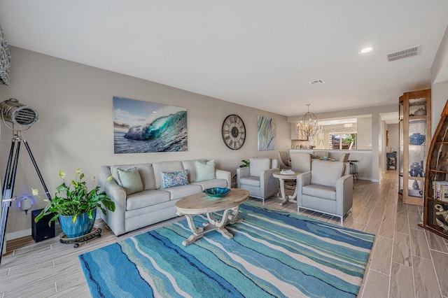 living room with visible vents, wood tiled floor, baseboards, and an inviting chandelier