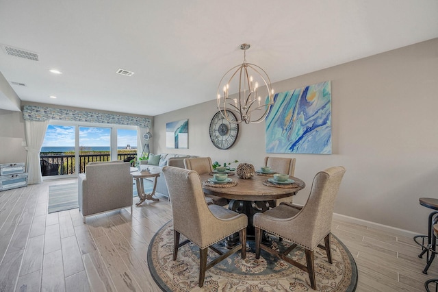 dining space with an inviting chandelier, light wood finished floors, baseboards, and visible vents