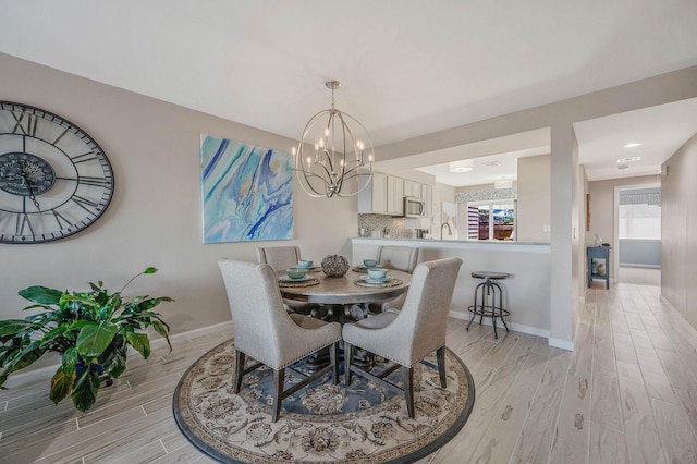 dining area featuring baseboards, a chandelier, and light wood-style flooring