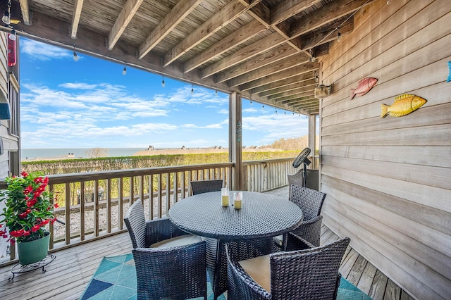 wooden terrace featuring outdoor dining space and a water view