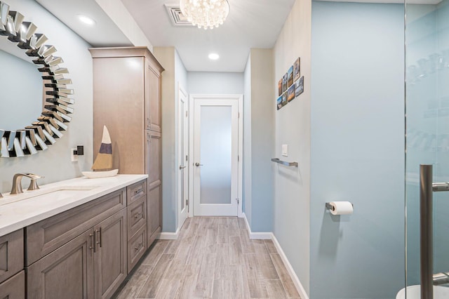 bathroom featuring visible vents, vanity, wood finished floors, baseboards, and a chandelier