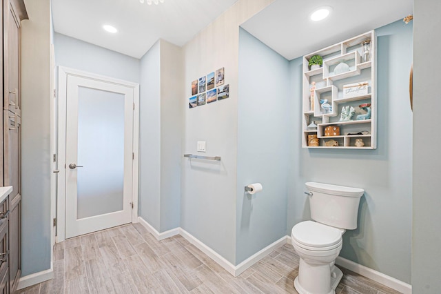 bathroom with baseboards, wood finished floors, and toilet
