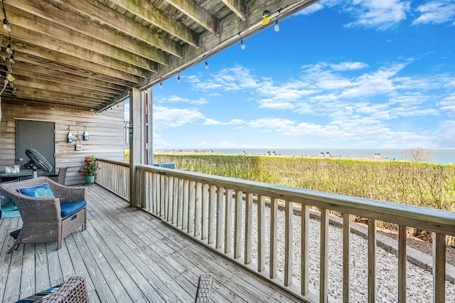wooden terrace featuring a water view and a view of the beach