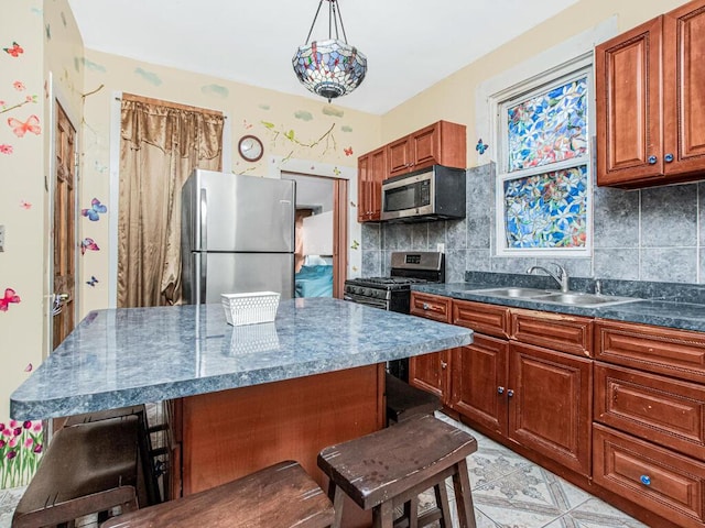 kitchen featuring a kitchen breakfast bar, tasteful backsplash, a sink, appliances with stainless steel finishes, and dark countertops