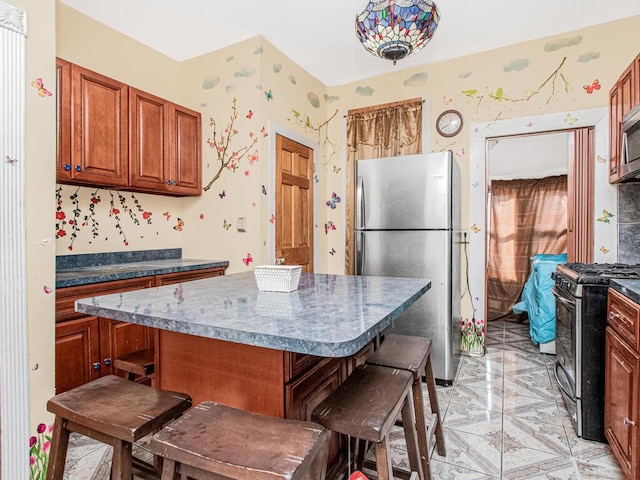 kitchen with a breakfast bar area, dark countertops, stainless steel appliances, a kitchen island, and brown cabinetry