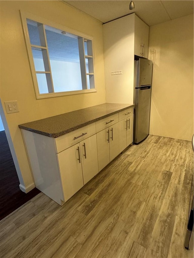 35 Park Ave Unit 1D, Suffern, NY 10901 - kitchen featuring dark countertops, white cabinets, freestanding refrigerator, and wood finished floors