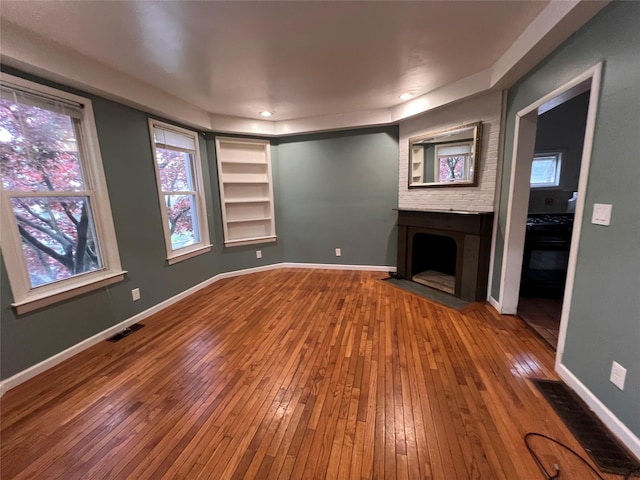57 Prince St, Middletown, NY 10940 - unfurnished living room featuring visible vents, a fireplace with flush hearth, built in features, and hardwood / wood-style floors