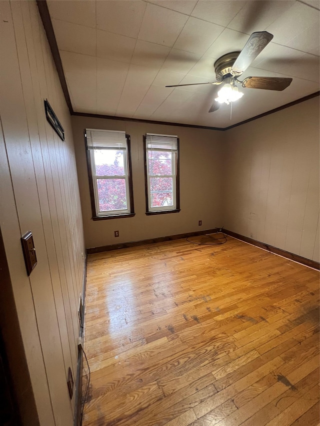57 Prince St, Middletown, NY 10940 - empty room with crown molding, wood walls, light wood-style floors, baseboards, and ceiling fan