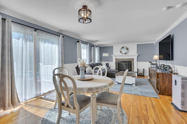 7 Karen Ct, Wading River, NY 11792 - dining room with light wood-type flooring, crown molding, a wainscoted wall, and a fireplace