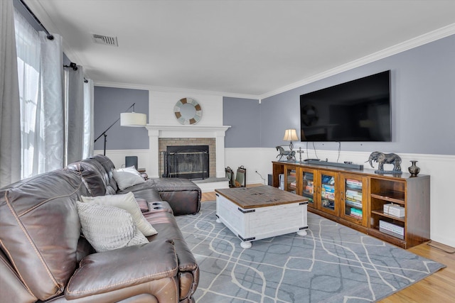 7 Karen Ct, Wading River, NY 11792 - living area with crown molding, visible vents, wainscoting, wood finished floors, and a fireplace