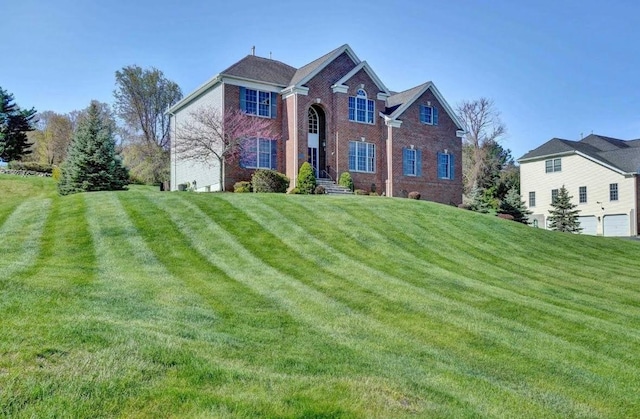 traditional-style home featuring a front yard and brick siding