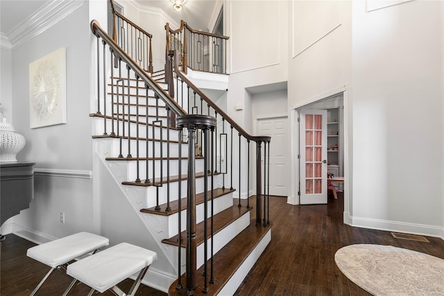 stairway featuring baseboards, ornamental molding, a high ceiling, and wood finished floors