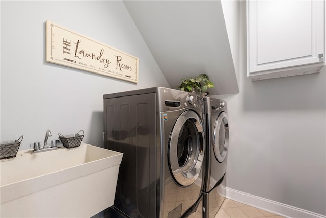 clothes washing area with cabinet space, a sink, baseboards, washing machine and dryer, and light tile patterned flooring