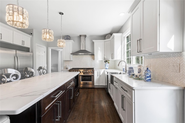 kitchen featuring white cabinetry, stainless steel appliances, dark wood finished floors, wall chimney exhaust hood, and a notable chandelier