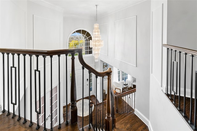 stairway with baseboards, wood finished floors, an inviting chandelier, and crown molding