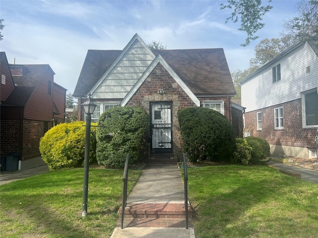 view of front of home featuring roof with shingles, stone siding, and a front lawn