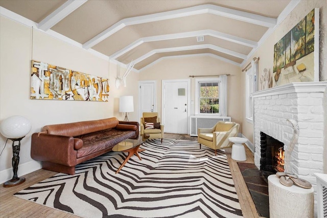 living room featuring vaulted ceiling, wood finished floors, baseboards, and a brick fireplace