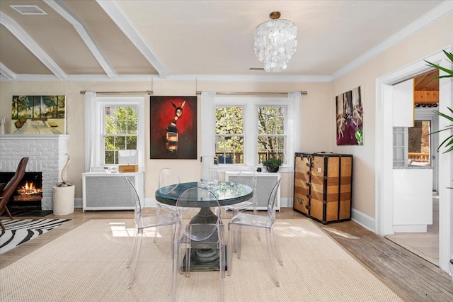 dining space with baseboards, visible vents, a brick fireplace, a chandelier, and wood finished floors