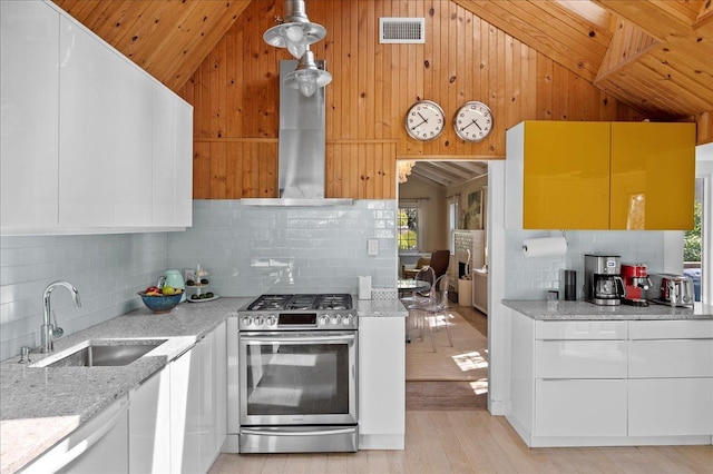 kitchen featuring stainless steel gas range oven, lofted ceiling, visible vents, and a sink