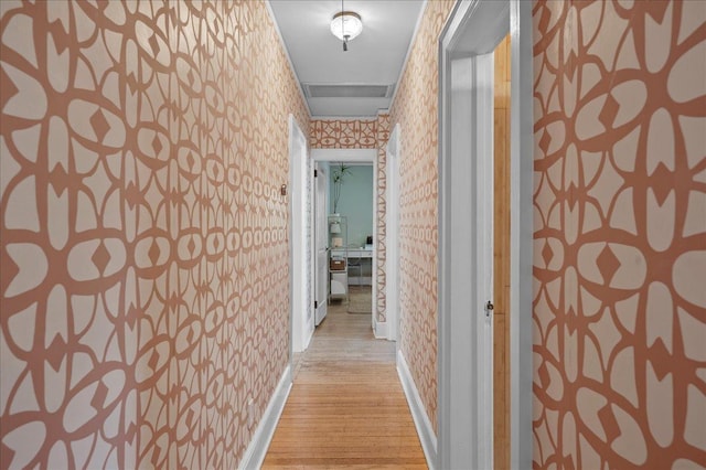 corridor with wallpapered walls, light wood-type flooring, and baseboards