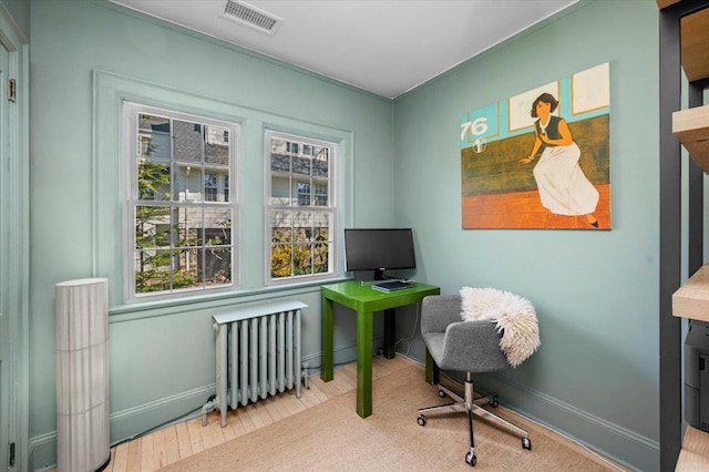 office with wood finished floors, visible vents, baseboards, and radiator heating unit