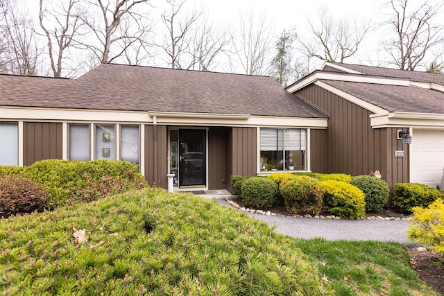 property entrance with an attached garage and a shingled roof