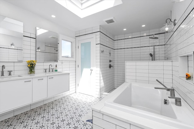 full bathroom featuring tile walls, a skylight, walk in shower, and a sink