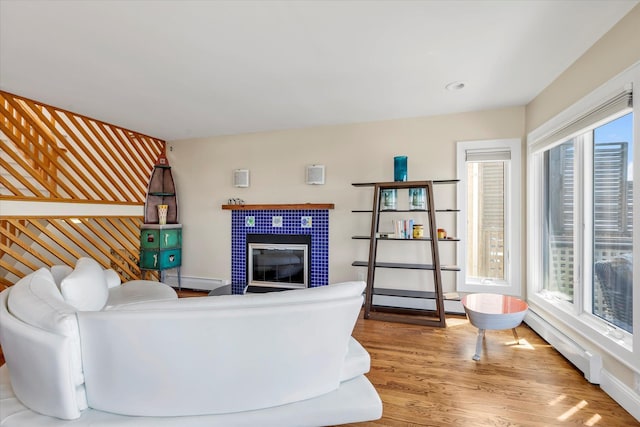 living area featuring baseboards, a baseboard heating unit, wood finished floors, and baseboard heating