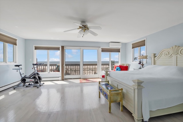 bedroom with a water view, access to outside, a wall mounted air conditioner, and wood finished floors