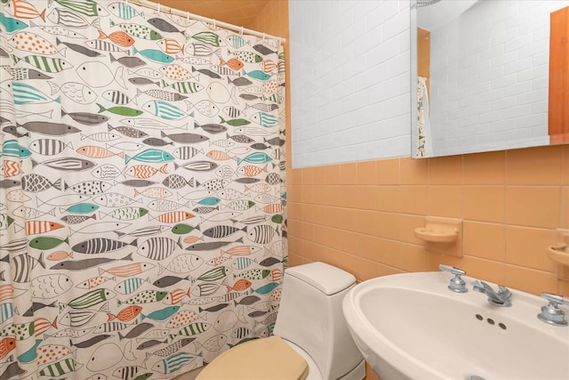 bathroom featuring a sink, curtained shower, toilet, and tile walls