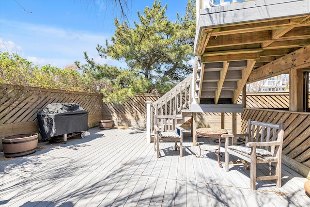 wooden deck with stairway, fence, and a grill
