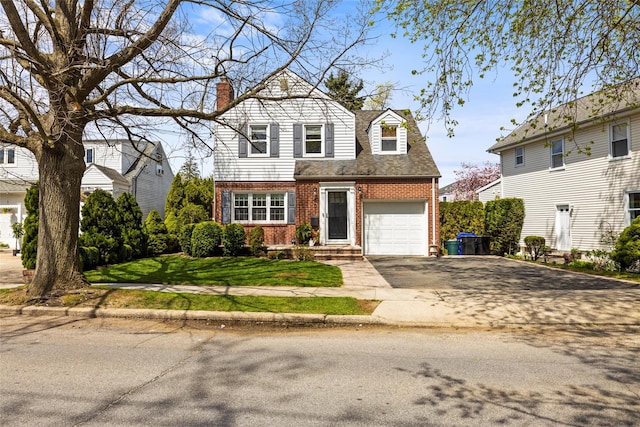 view of front of home with brick siding, roof with shingles, driveway, and a chimney