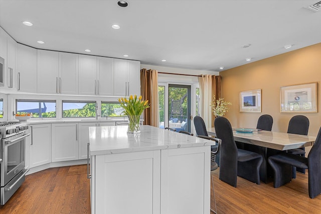 kitchen with visible vents, gas range, light stone countertops, white cabinetry, and dark wood-type flooring